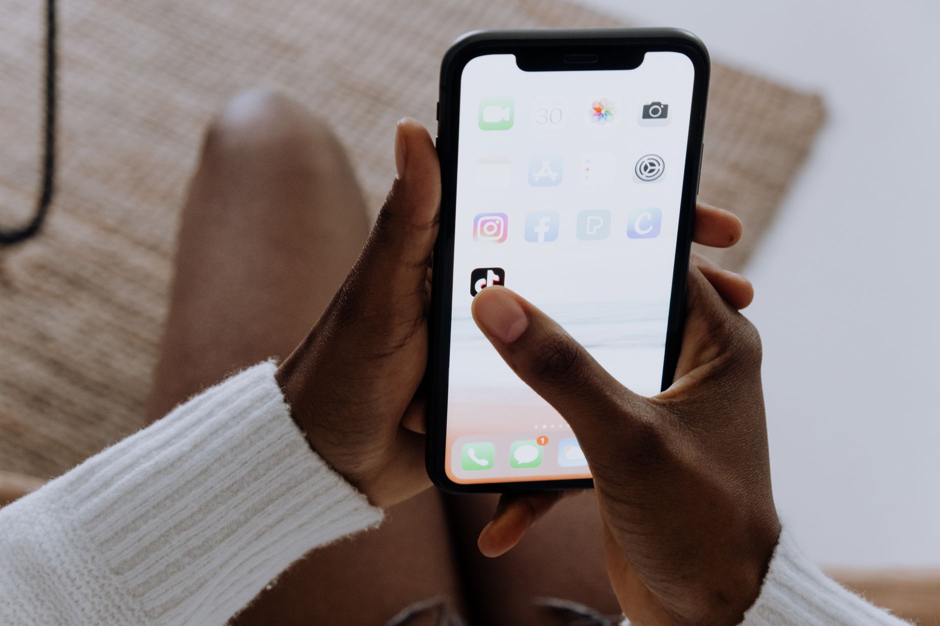 Black person's hands tapping the TikTok app on a smartphone, representing TikTok marketing for Nigerian brands. Photo by Pexels.