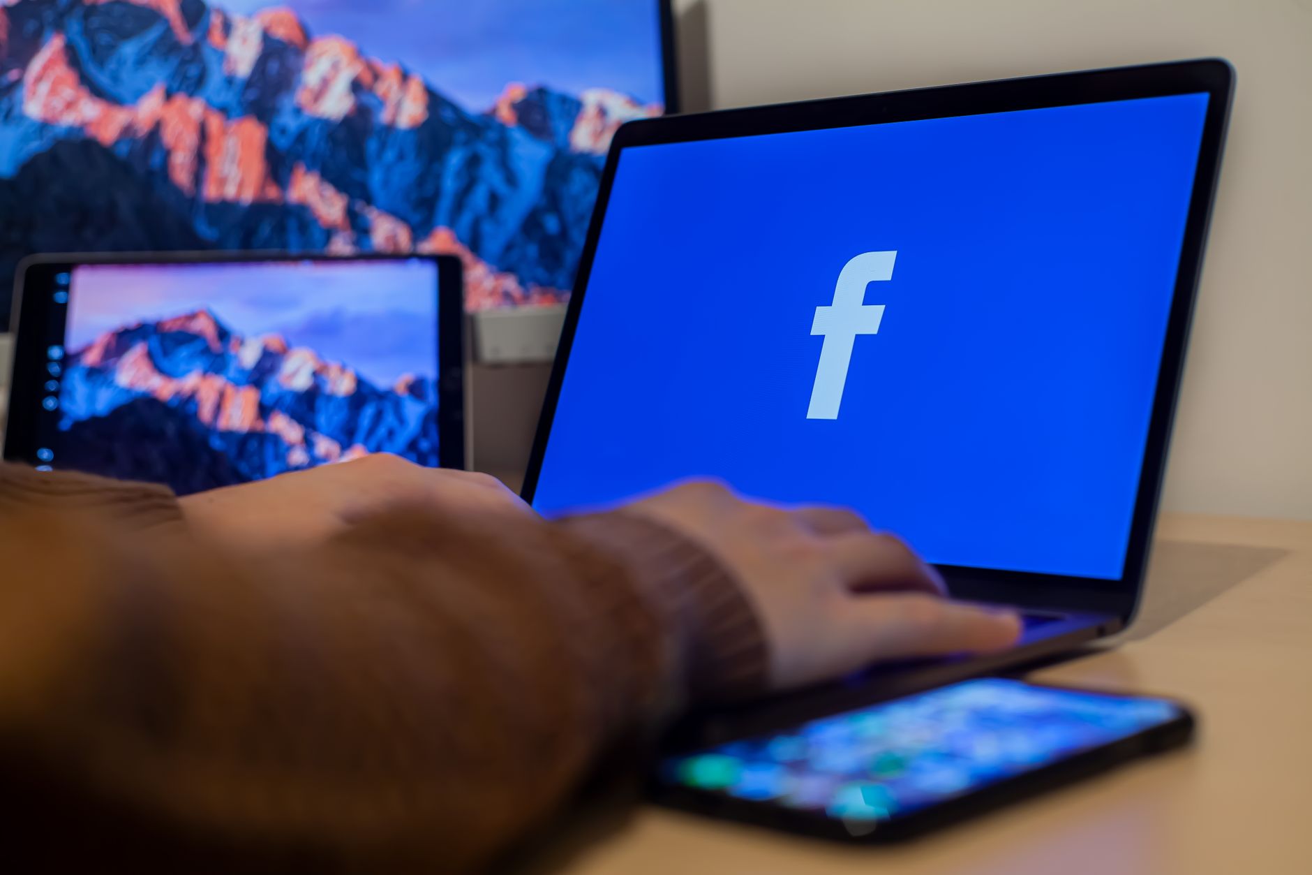 Facebook logo on a laptop screen at a desk workspace used for running ad campaigns