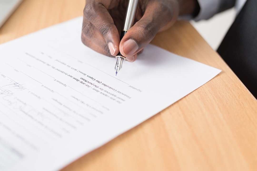 Person signing a business contract document with a pen — protecting your business with the right contract clauses when hiring a digital marketer in Nigeria