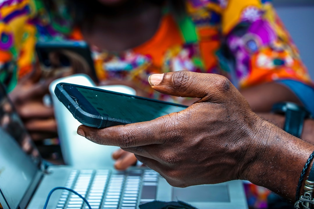 African business owner using smartphone and laptop for digital marketing in Nigeria. Photo by Unsplash.