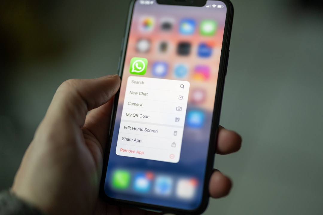 Hand holding an iPhone with WhatsApp app highlighted on the home screen, showing the app Nigerian SMEs use for customer communication