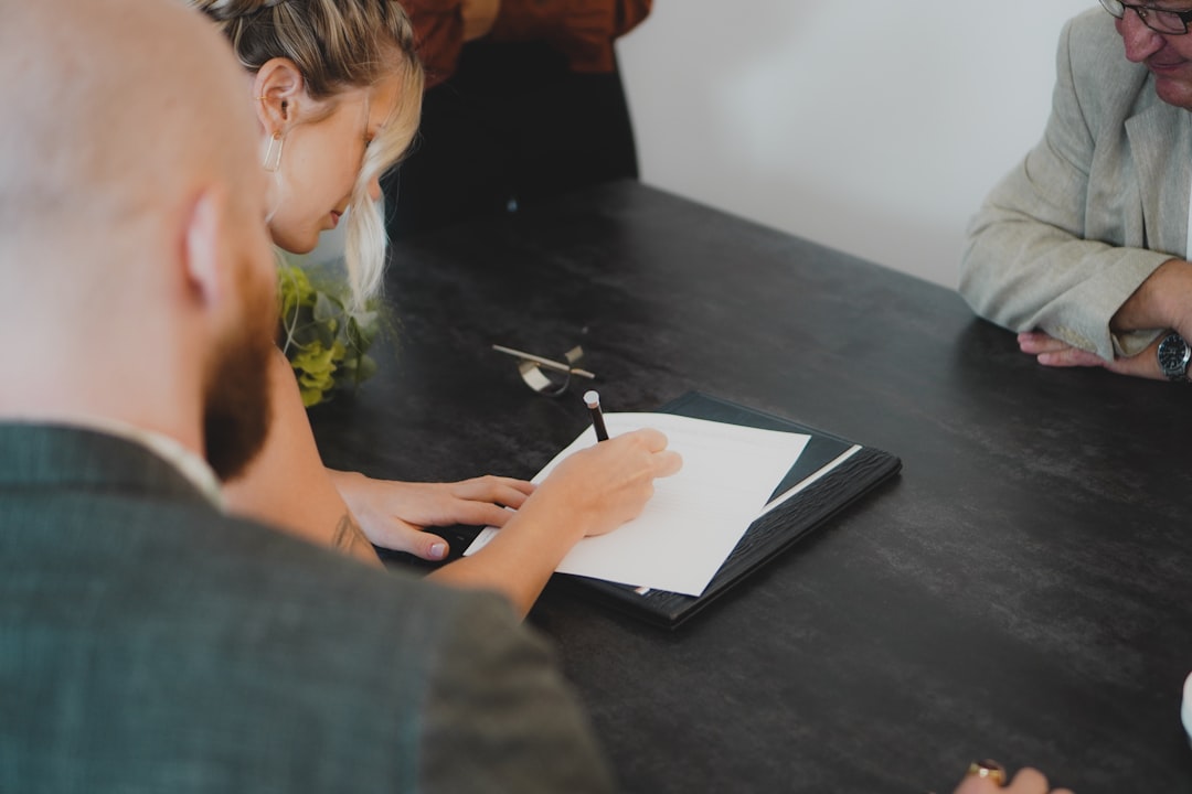 Business professional reviewing and signing documents at a meeting table before committing to a contract