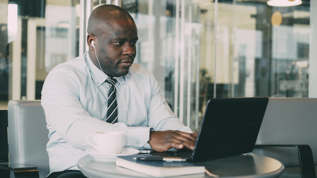 African American businessman in formal wear working on a laptop in a corporate office environment, representing professional SEO services in Nigeria